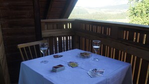 Ein Tisch im Freien mit Blick auf die Landschaft, eine Holzterrasse und eine weiße Tischdecke.
