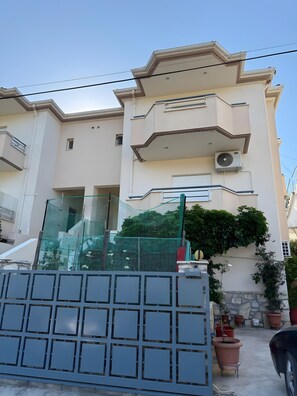 A multi-story building with balconies, a gated entrance, and potted plants. - Apartment 'Family Home' with Sea View, Wi-Fi and Air Conditioning (Agios Konstantinos)
