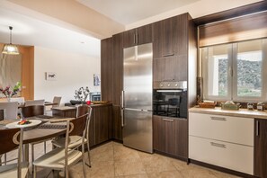 Una cocina moderna con armarios de madera oscura, electrodomésticos de acero inoxidable y una zona de comedor con mesa y sillas.