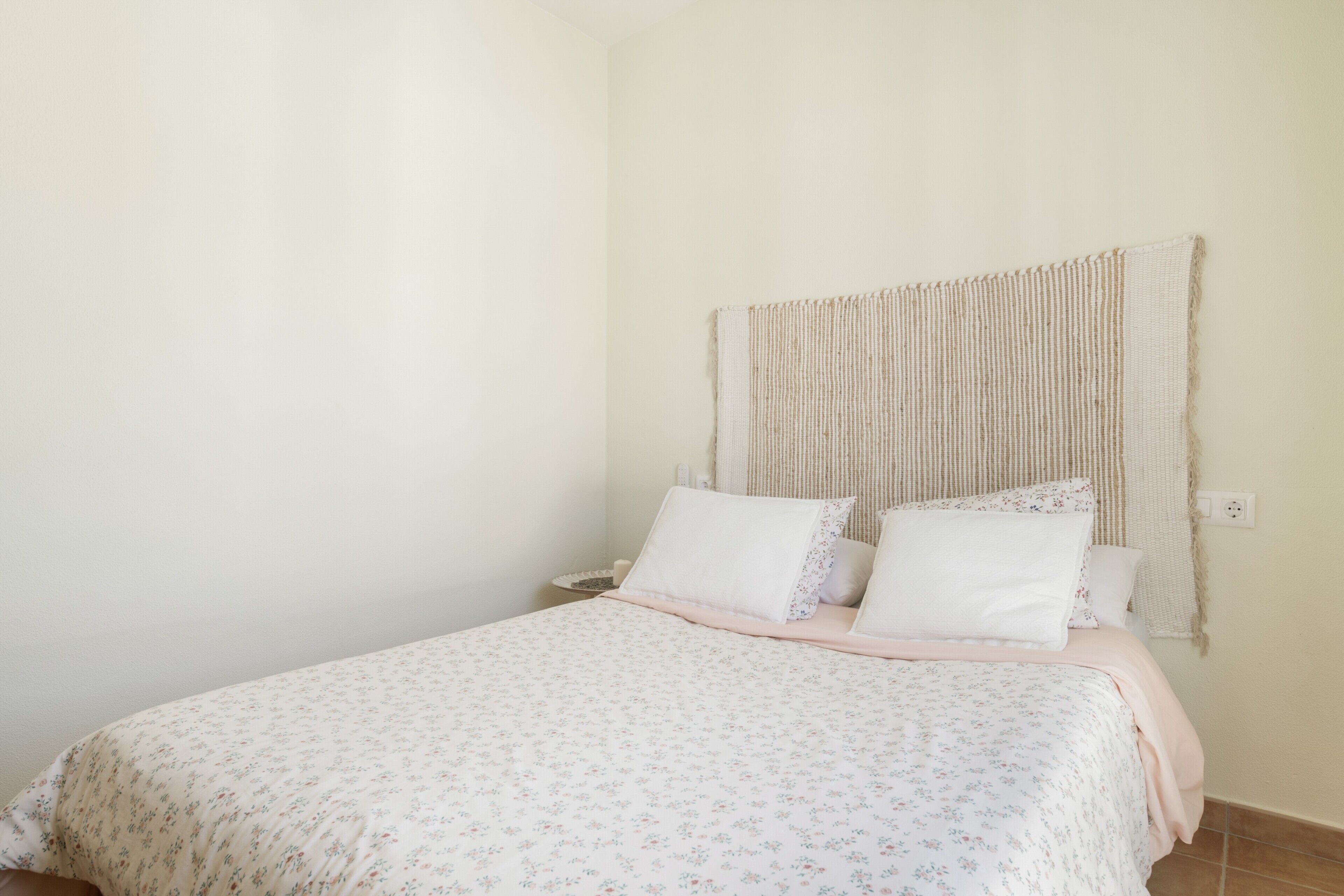 Ein Schlafzimmer mit einem Bett, Kissen, einem Wandpaneel als Kopfteil und einem Nachttisch.