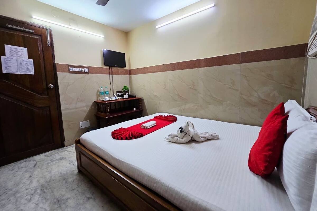 Una habitación de hotel con una cama, un televisor de pantalla plana, una mesita de noche de madera y una puerta con un aviso.
