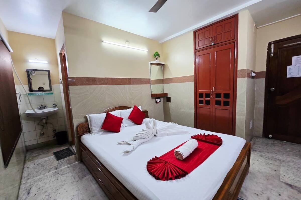 Una habitación de hotel con cama, espejo, lavamanos y armario.