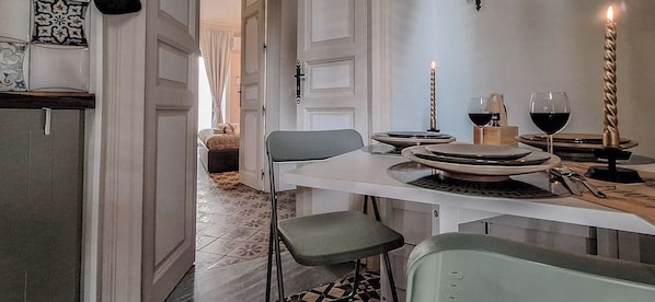 A dining area with a table set for two, a candle, and a wine glass. - Suite Home Vincenzo Bellini (Caltanissetta)