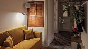 A room with a sofa, a door with a mirror, and a plant on a table. - Suite Home Vincenzo Bellini (Caltanissetta)