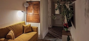 Una habitación con un sofá, una puerta con espejo y una planta sobre una mesa.