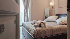 A neatly made bed with a quilted cover, a set of towels, and a bedside table with a lamp. - Suite Home Vincenzo Bellini (Caltanissetta)