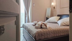 Una cama bien hecha con cubrecama acolchado, una mesita de noche con lámpara y un espejo en la pared.