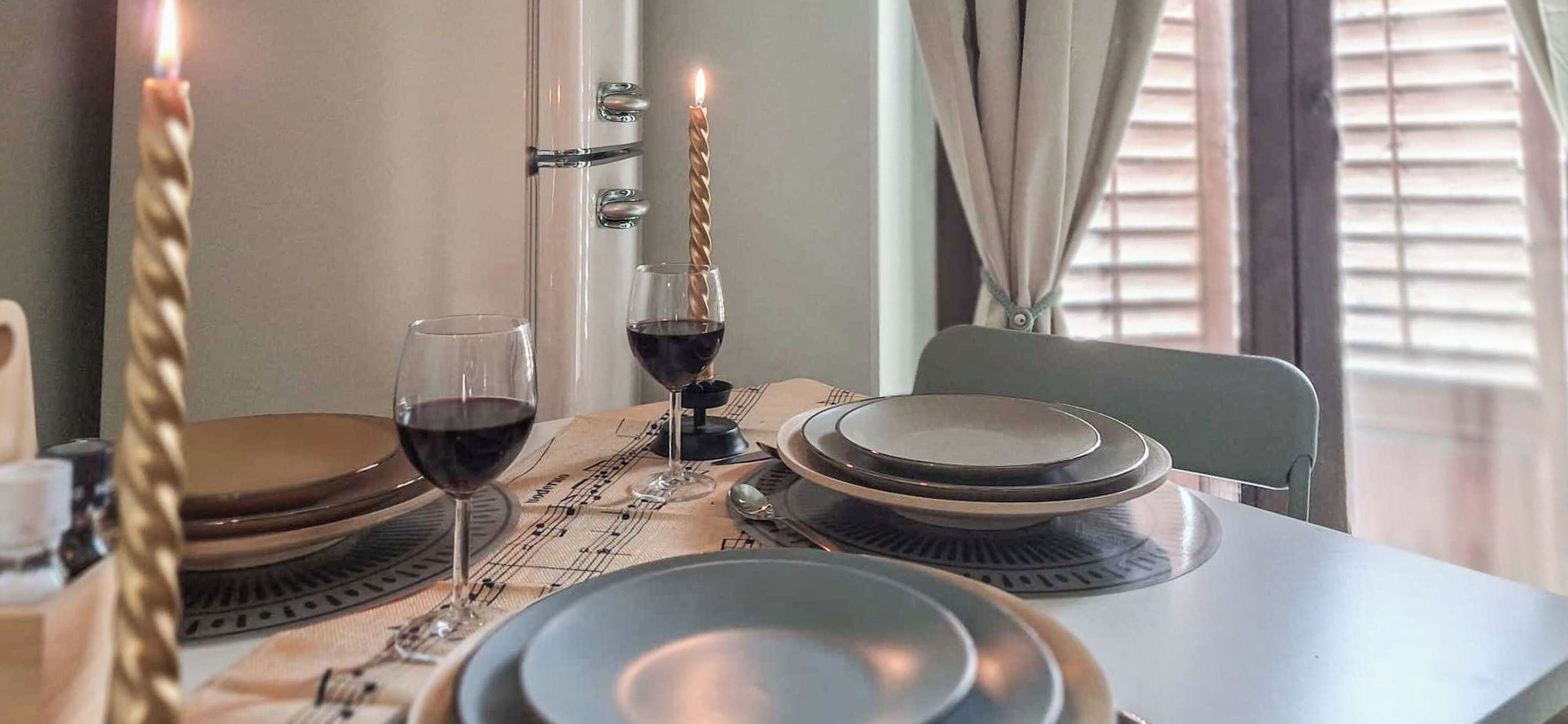 A dining table set with plates, glasses, and a candle.