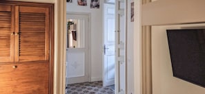 Un pasillo con puertas de madera, una puerta blanca con un panel decorativo y un suelo con diseño.