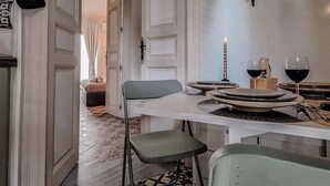 Un comedor con una mesa dispuesta para dos personas, una vela, una copa de vino y un candelabro.
