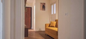 A hallway with a wooden door, a yellow sofa, and a framed picture on the wall. - Suite Home Vincenzo Bellini (Caltanissetta)