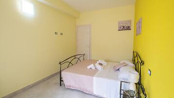 Un dormitorio con cama, puerta y lámpara fijada a la pared.