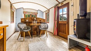 A cozy room with a wooden table and chairs, a fireplace, and a window with curtains. - Hamble Brook in Oakengrove Vineyard (Buckinghamshire)