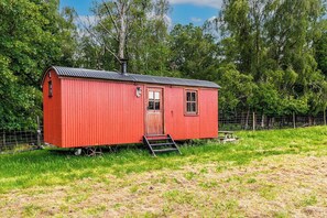 A red metal structure with a door, windows, and a chimney.