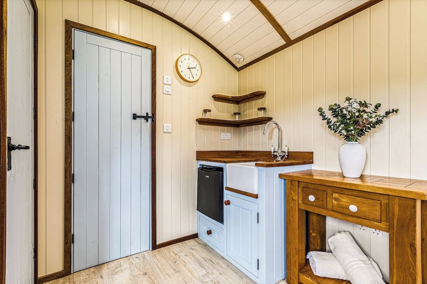 A kitchen with a sink, a clock, and a plant.