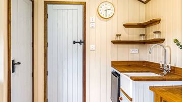 Une cuisine avec des meubles de rangement en bois, un évier, une horloge et une porte.