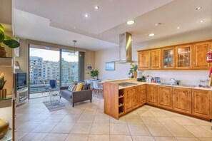Eine moderne Küche mit Holzausstattung, ein Essbereich mit einer Couch und ein großes Fenster mit Blick auf die Stadt.