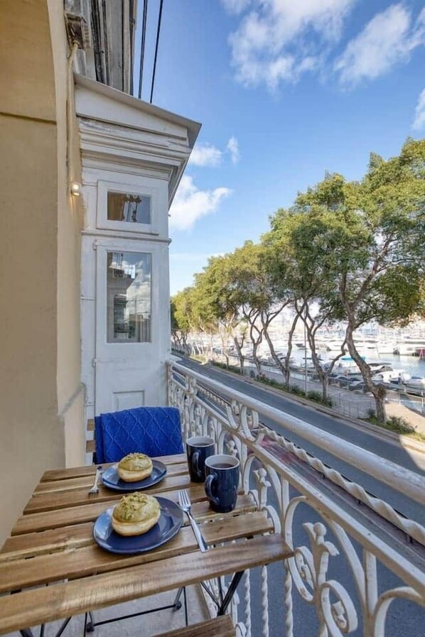 A balcony with a table, chairs, and a view of the marina. - Valletta Marina View - Seafront Apartment (Pietà)
