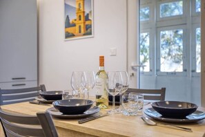 A dining table set with wine glasses, a bottle, and bowls. - Valletta Marina View - Seafront Apartment (Pietà)