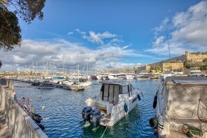 A marina with boats docked, a clear sky, and a historic building in the background. - Valletta Marina View - Seafront Apartment (Pietà)