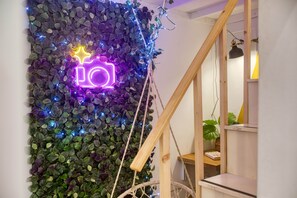 A wall with a neon sign, a wooden staircase, and a plant. - Casa Botanica, charming Maltese townhouse (Luqa)