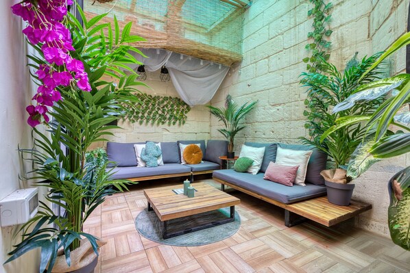 A cozy indoor seating area with a sofa, a coffee table, and various potted plants. - Casa Botanica, charming Maltese townhouse (Luqa)