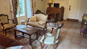 Een woonkamer met een bank, fauteuils, een salontafel, een televisie en een kast.