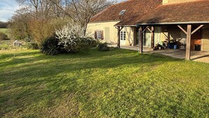 Een landelijk gebouw met een overdekte veranda, een gazon en bomen.