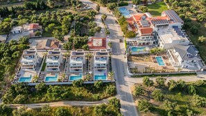Luftaufnahme eines Resorts mit mehreren Gebäuden, Pools und einer Zufahrtsstraße.