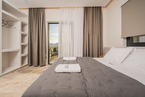 Ein Hotelzimmer mit einem großen Bett, einem Kleiderschrank und Blick durch eine Glastür.