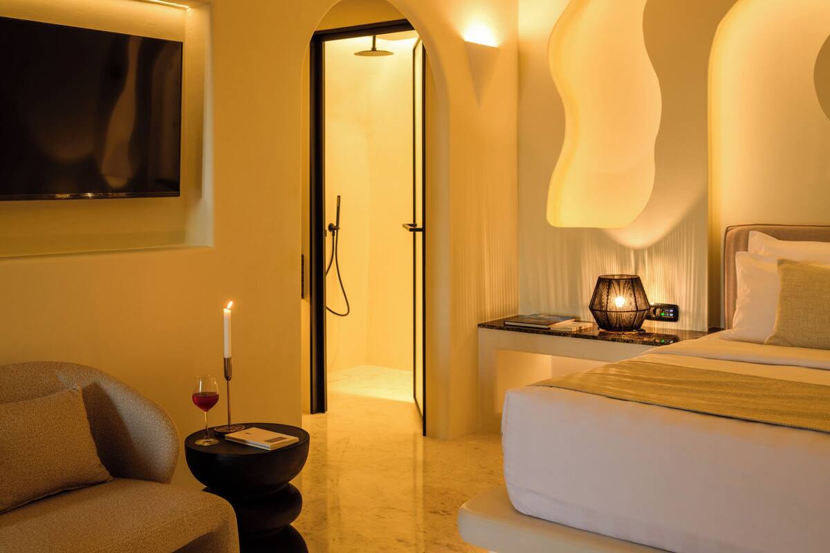 Une chambre d’hôtel comprenant un lit, une table de chevet, une lampe, un téléviseur et une porte donnant sur une salle de bain.