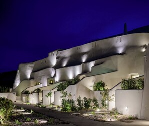 A modern building with a unique architectural design, featuring a curved facade and a pathway leading to the entrance. - Avelora Suites (Pyrgos Kallistis)