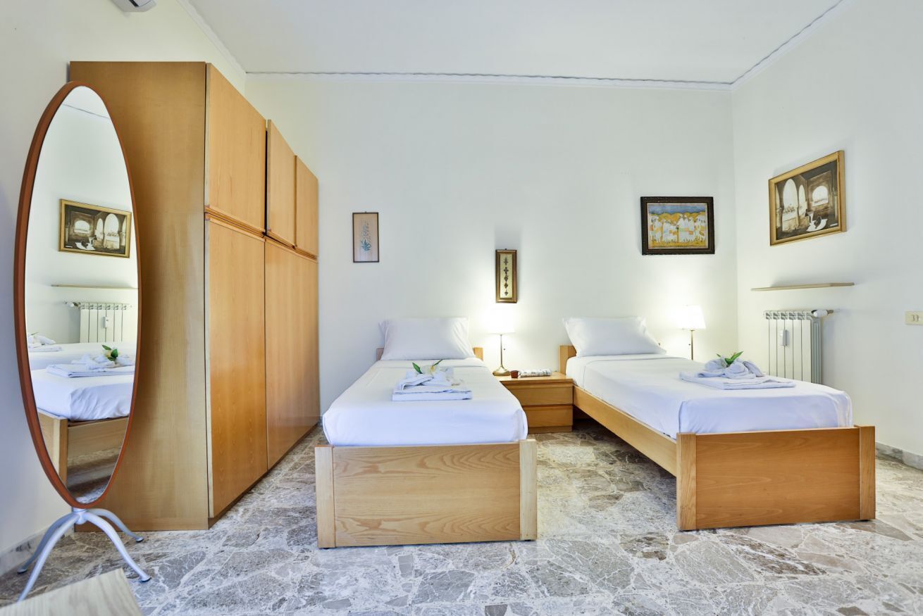 Ein Hotelzimmer mit zwei Betten, einem Holzschrank, einem Spiegel und Bildern an den Wänden.