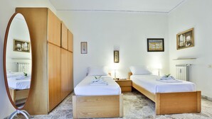 Ein Hotelzimmer mit zwei Betten, einem Holzschrank, einem Spiegel und Bildern an den Wänden.