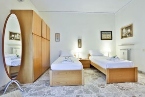 Una camera d'albergo con due letti, un armadio in legno, uno specchio e opere d'arte alle pareti.