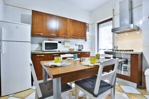 Una cucina moderna con mobili in legno, un frigorifero bianco, un forno a microonde e un tavolo da pranzo con sedie.
