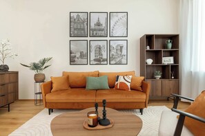 A living room with a sofa, a coffee table, a bookshelf, and framed pictures on the wall. - Charming Apartment in the City Center | Crib and High Chair (Gdańsk)