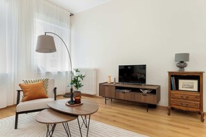 En stue med sofa, sofabord, fjernsyn, skab og lampe.