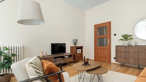 Una sala moderna con sofá, televisor, mueble de madera y mesa de comedor.