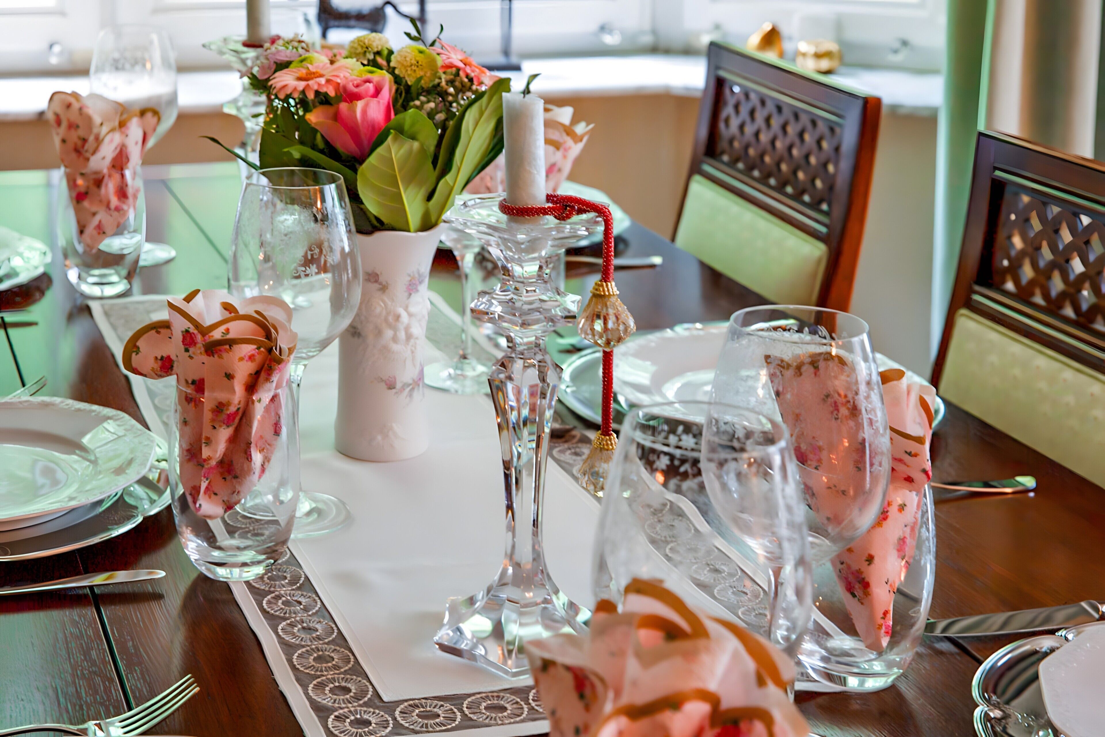 Una mesa de comedor dispuesta con cristalería, platos y un centro de mesa con flores.