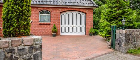 A brick house with a large white garage door, a small window, and a potted plant.