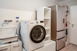 Ein Waschraum mit einer Waschmaschine, einem Waschbecken und einem Kühlschrank.