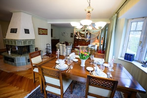 Une salle à manger avec une cheminée, des meubles en bois et un lustre.
