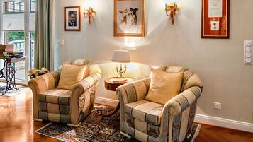 A living room with two armchairs, a side table, a lamp, and a framed picture on the wall.