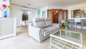 En moderne stue med en sofa, et sofabord i glas og et spiseområde med stole.