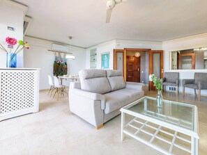 Ein modernes Wohnzimmer mit einer Couch, einem Glastisch und einem Essbereich mit Stühlen.