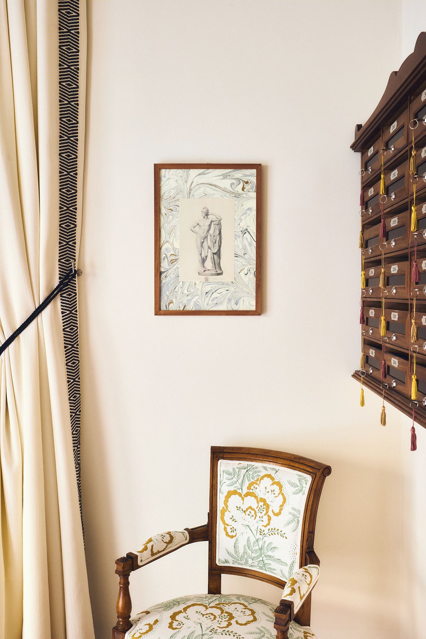 Una stanza con una sedia, un quadro incorniciato e un mobile a parete.