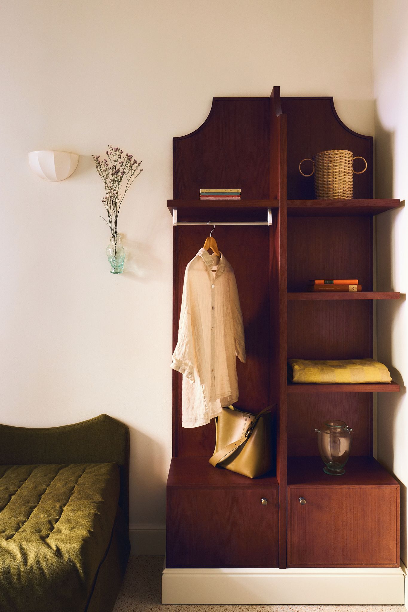A wooden wardrobe with a hanging rod, shelves, and a small cabinet.