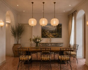 A dining room with a wooden table, four chairs, a vase with flowers, a bust on a mantelpiece, and a landscape painting on the wall. - Anchor Santa Croce (Firenze)