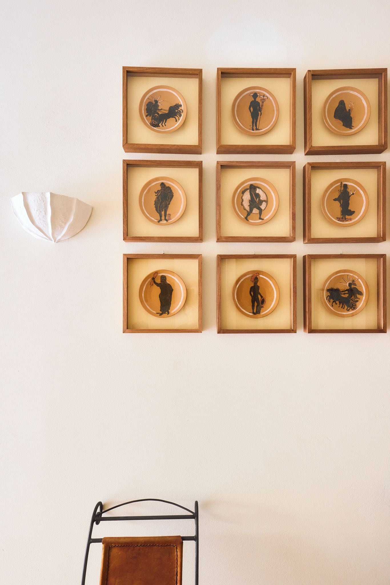 Un mur orné de neuf silhouettes encadrées représentant des personnages historiques et des animaux, disposées selon une grille de 3 sur 3.